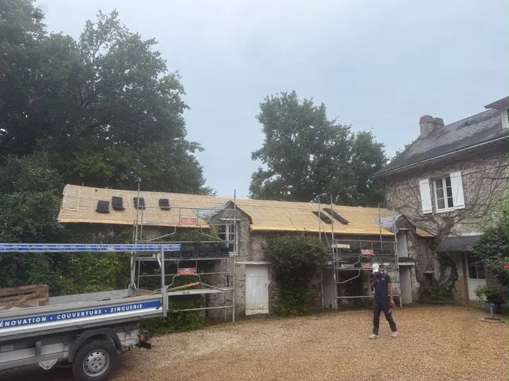 Liteaux apparents sur la toiture d’un bâtiment en pierre, au-dessus des échafaudages.