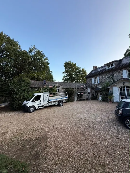 Bâtiment en pierre avec couverture existante, échafaudage et véhicule de chantier.